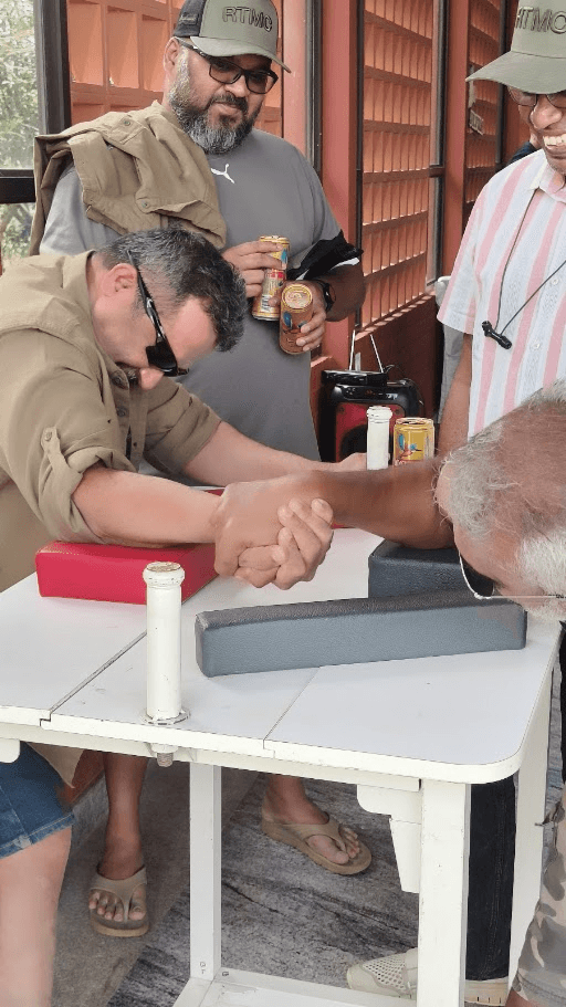 Two RTMC riders arm-wrestling outside the venue, with other members watching.